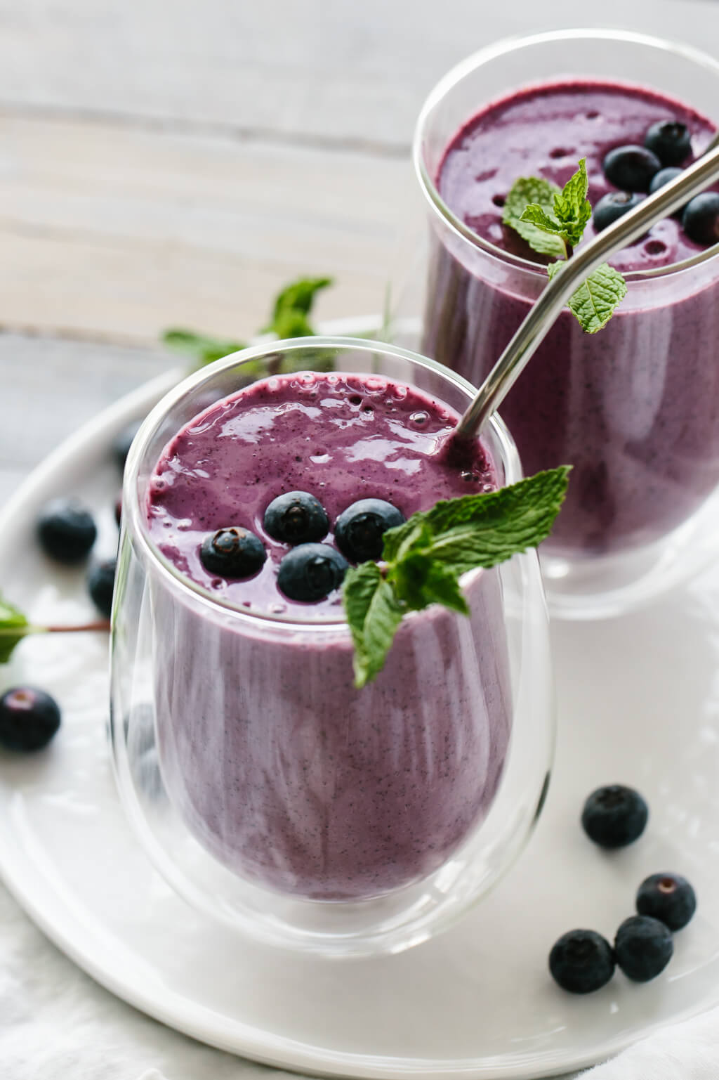 Blueberry smoothie in a glass with straw.