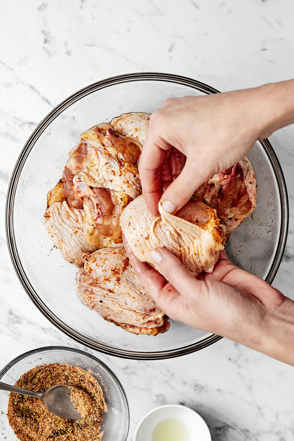 Adding seasoning to chicken thighs.