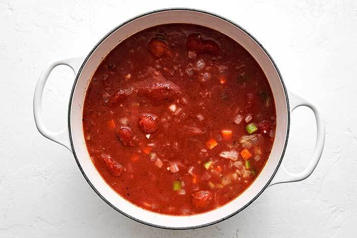 Cooked tomato soup in a white pot.