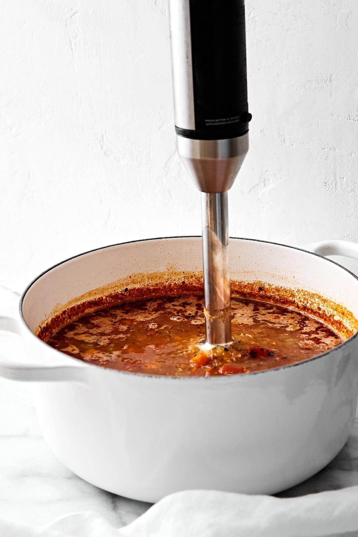 Lentil soup is the perfect vegetarian meal to cozy up with for fall and winter. It’s hearty, healthy, and wonderfully filling thanks to its plant-based protein. And while there are many variations of lentil soup, this simple and vibrant Mediterranean version is extra special. Blending lentil soup in a pot with immersion blender.