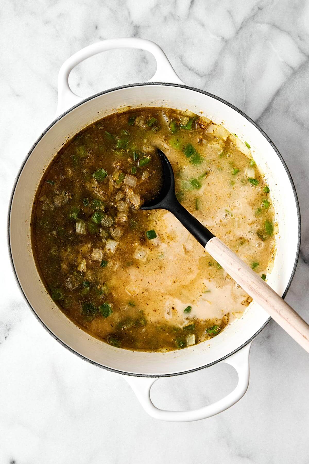 This white chicken chili is a fall/winter comfort food favorite and a flavorful blend of tender chicken, white beans, sweet corn, green chiles, and more! A pot cooking white chicken chili.
