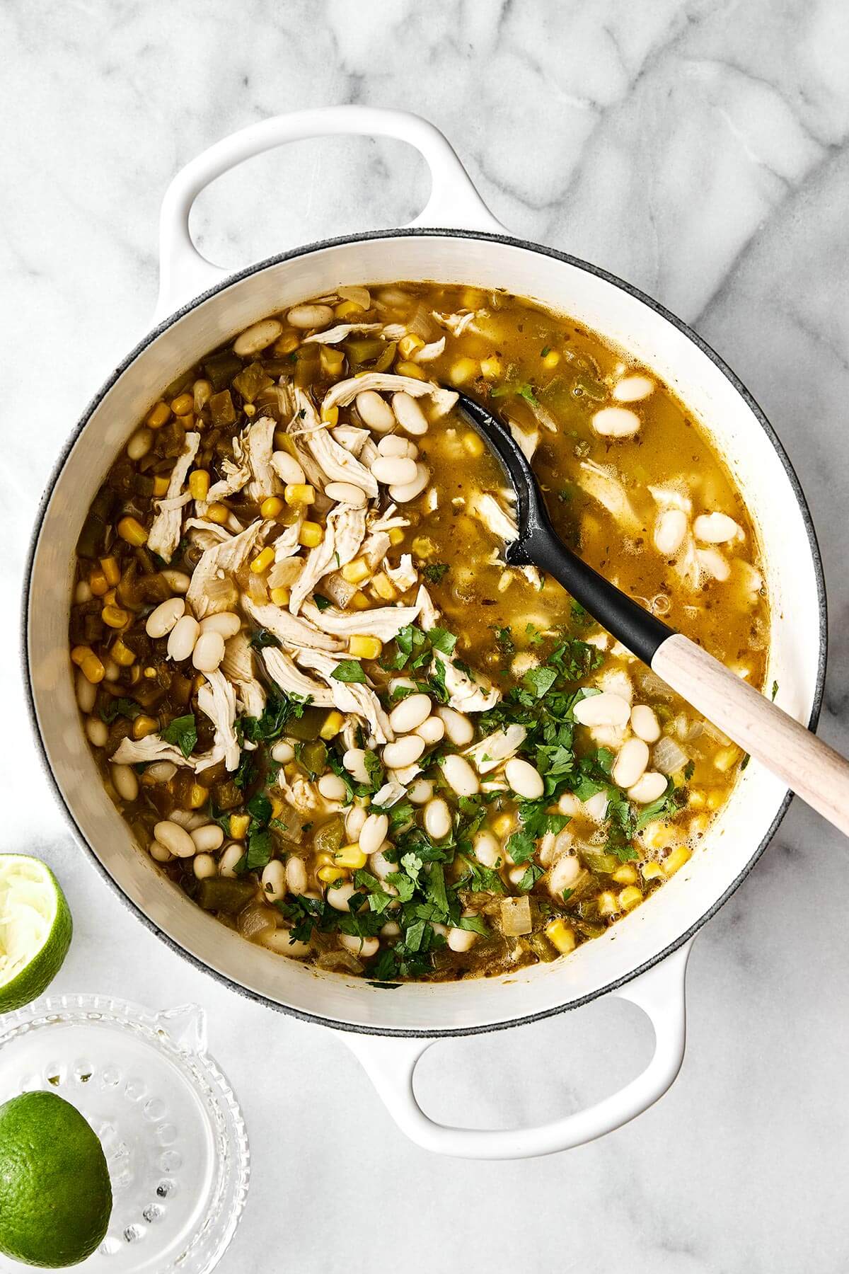This white chicken chili is a fall/winter comfort food favorite and a flavorful blend of tender chicken, white beans, sweet corn, green chiles, and more! Simmering white chicken chili in a pot.